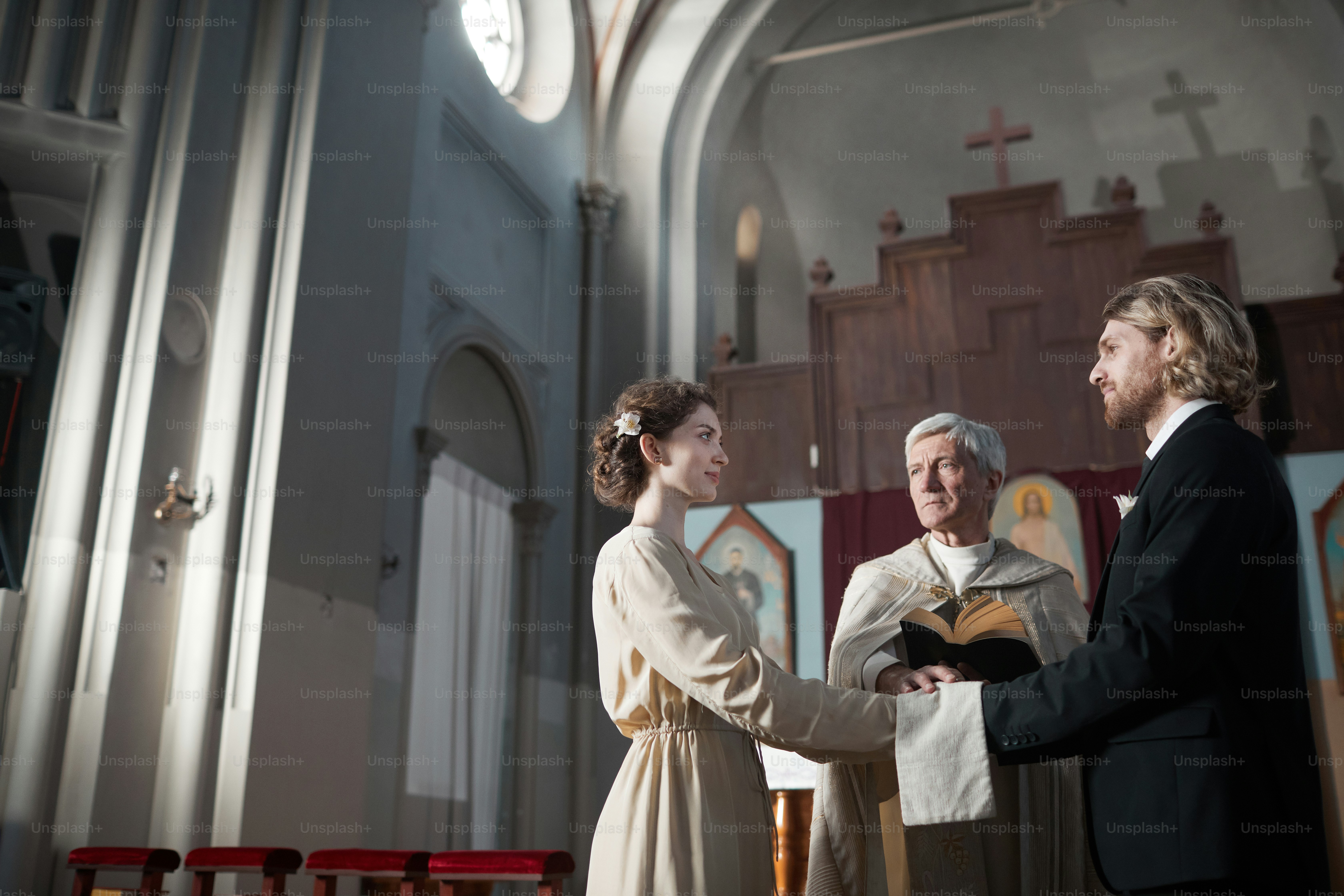 Young couple getting married in the church while priest reading the prayers