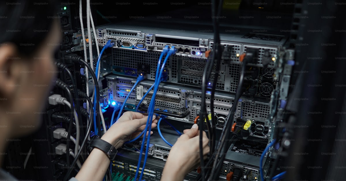 Close up of female network technician connecting cables in server ...