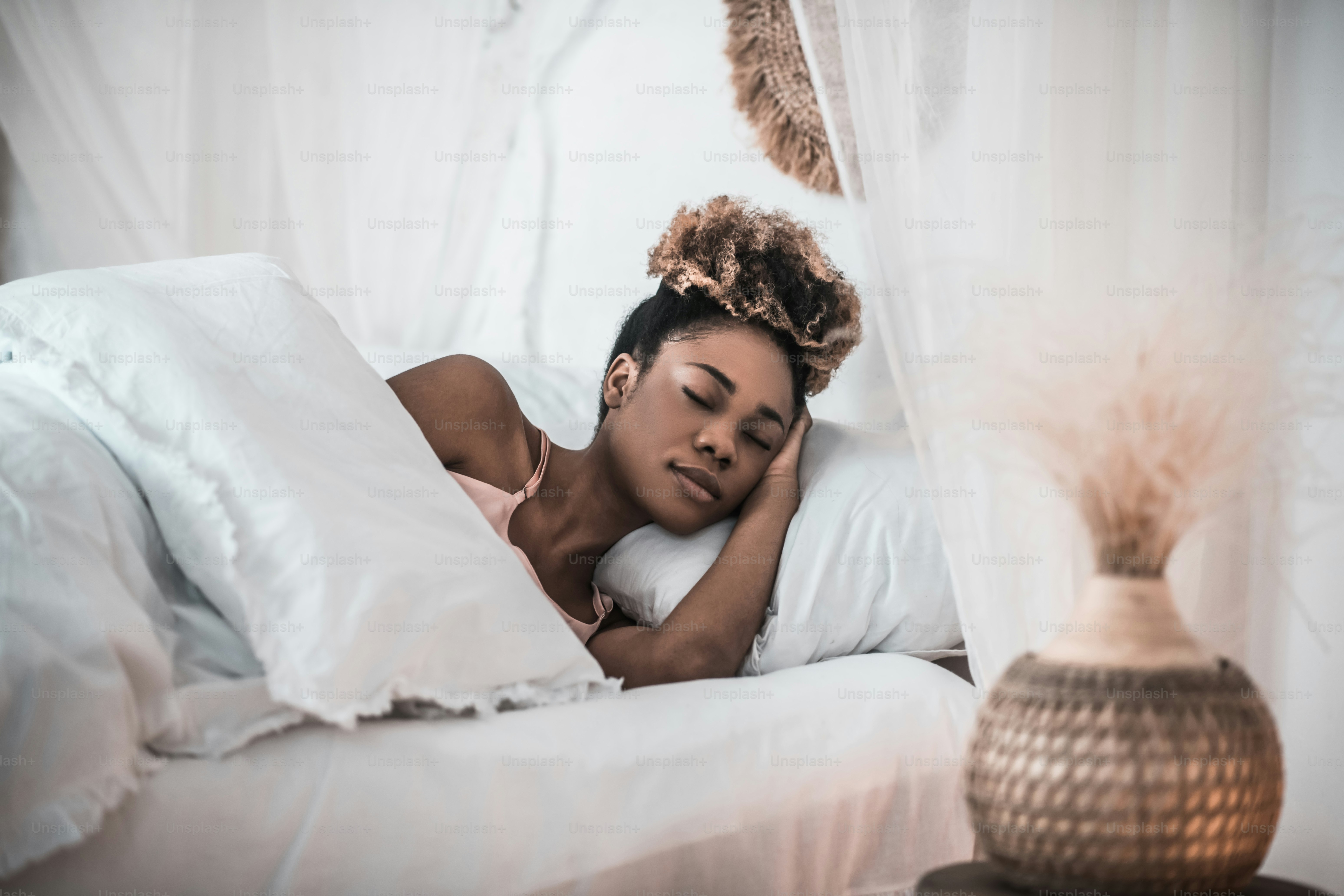 Heavy sleeper. Dark skinned young adult pretty woman sleeping in white bed in light bedroom