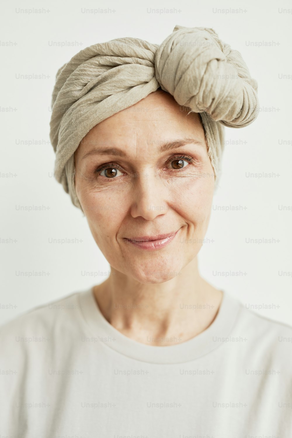 Minimal close up portrait of beautiful mature woman wearing headscarf and smiling at camera