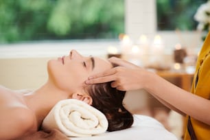 Primer plano de una joven y hermosa mujer relajándose durante el masaje en el salón de spa