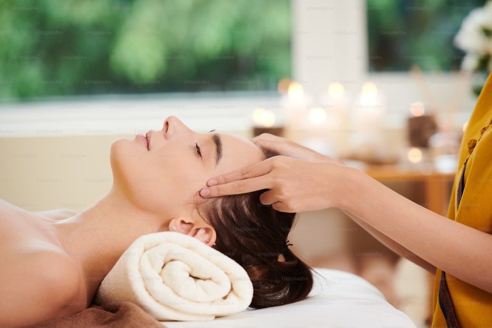 Close-up of young beautiful woman relaxing during massage in spa salon