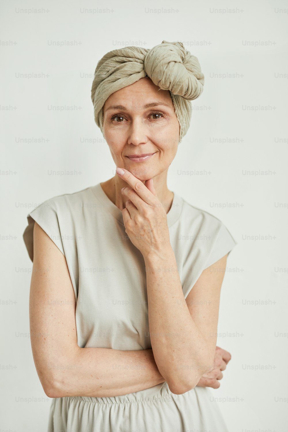 Retrato minimalista de cintura para arriba de una hermosa mujer madura con pañuelo en la cabeza y vestido mientras sonríe a la cámara