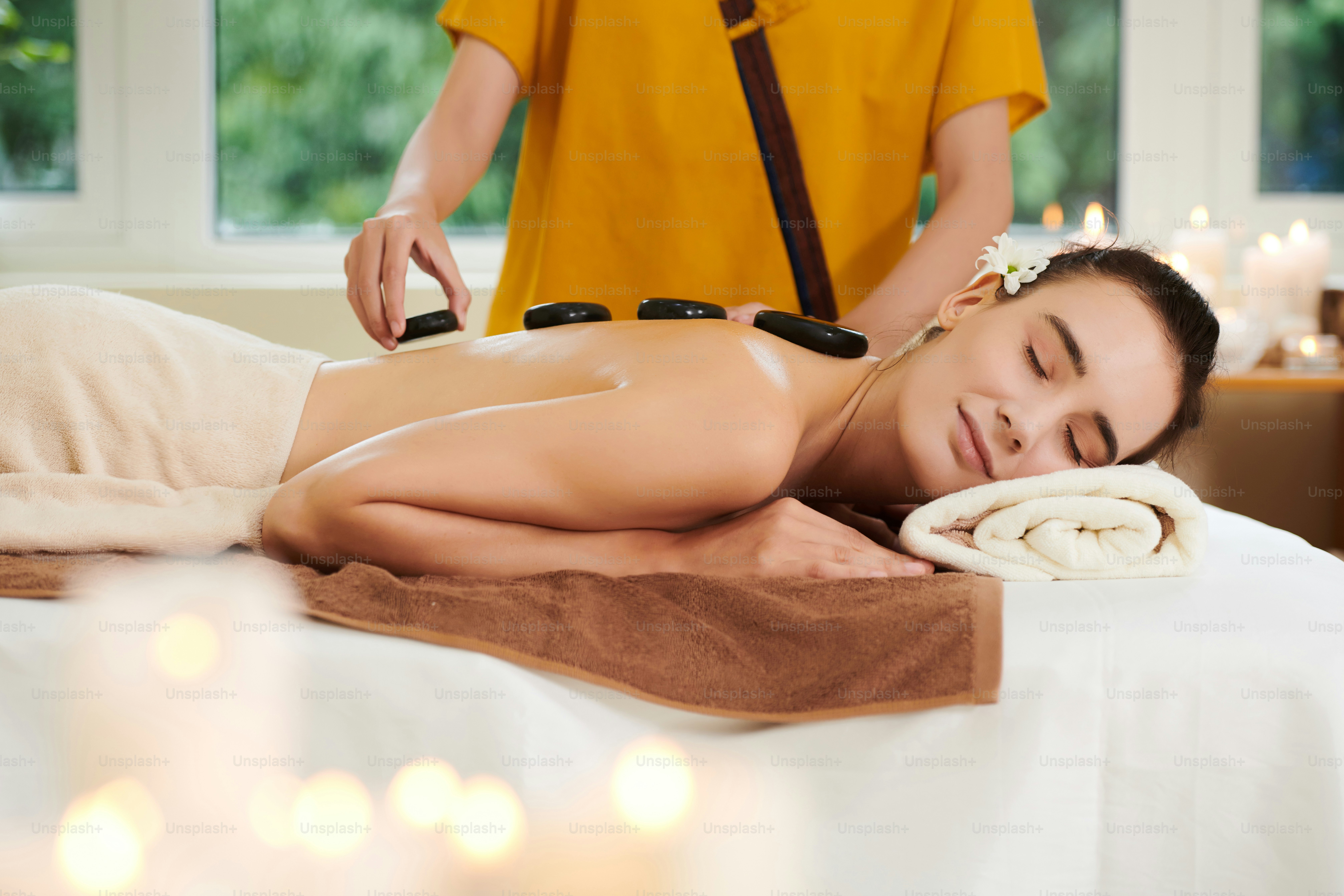 Jeune femme se relaxant pendant la thérapie par la pierre dans le salon de spa