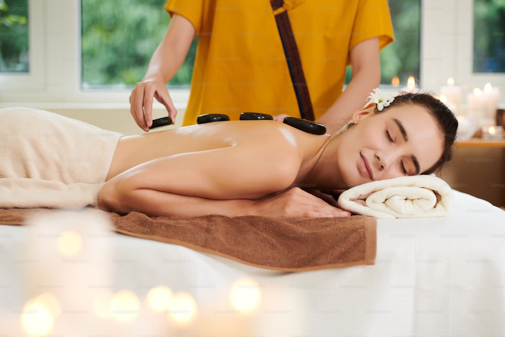 Young woman relaxing during stone therapy in spa salon