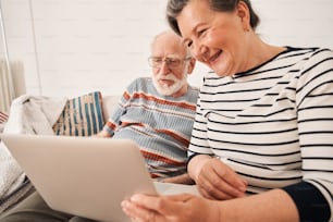 Cropped view of the senior couple holding video call with their family or friends from the laptop while spending pastime at the retirement house