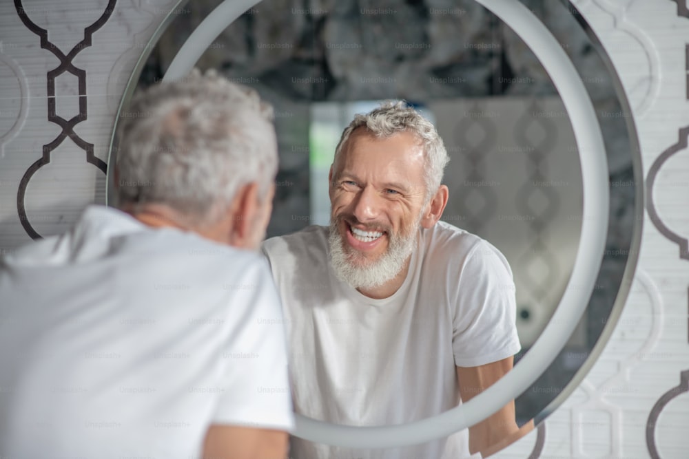 �かっこいい。鏡を見つめる笑顔の白髪の男