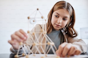 Portrait of teen girl making models while enjoying art and craft class in school