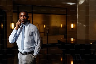 Portrait à la taille d’un bel homme d’affaires afro-américain parlant par smartphone au soleil, espace de copie