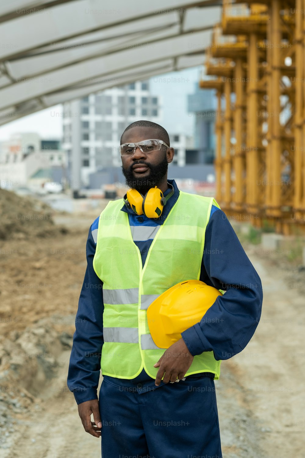 African young male builder in uniform standing on construction site
