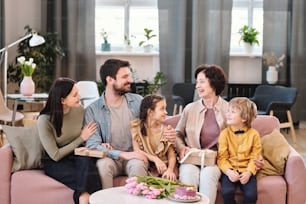 Big family of five sitting on sofa in home environment