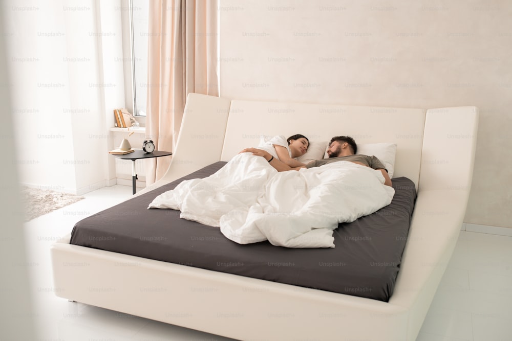Müdes junges Paar, das im Bett im Hotelzimmer schläft