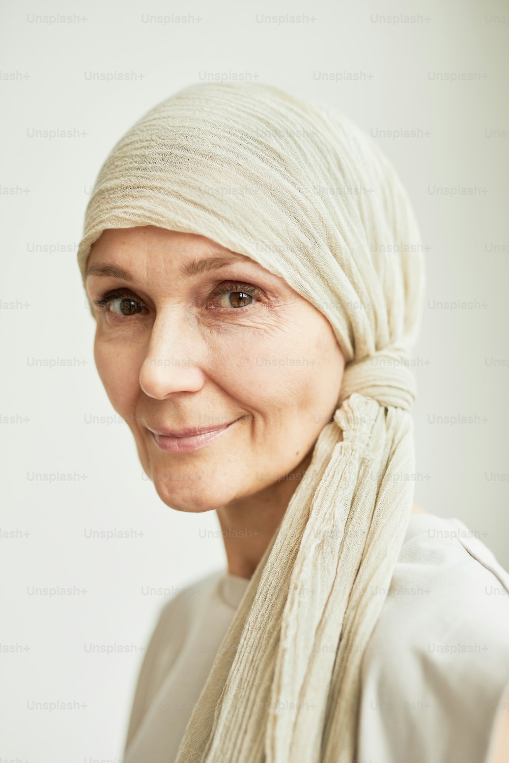 Minimal headshot portrait of beautiful mature woman wearing headscarf and looking at camera