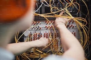 Primo piano dell'ingegnere di rete che collega i cavi nella sala server durante i lavori di manutenzione nel data center, spazio di copia