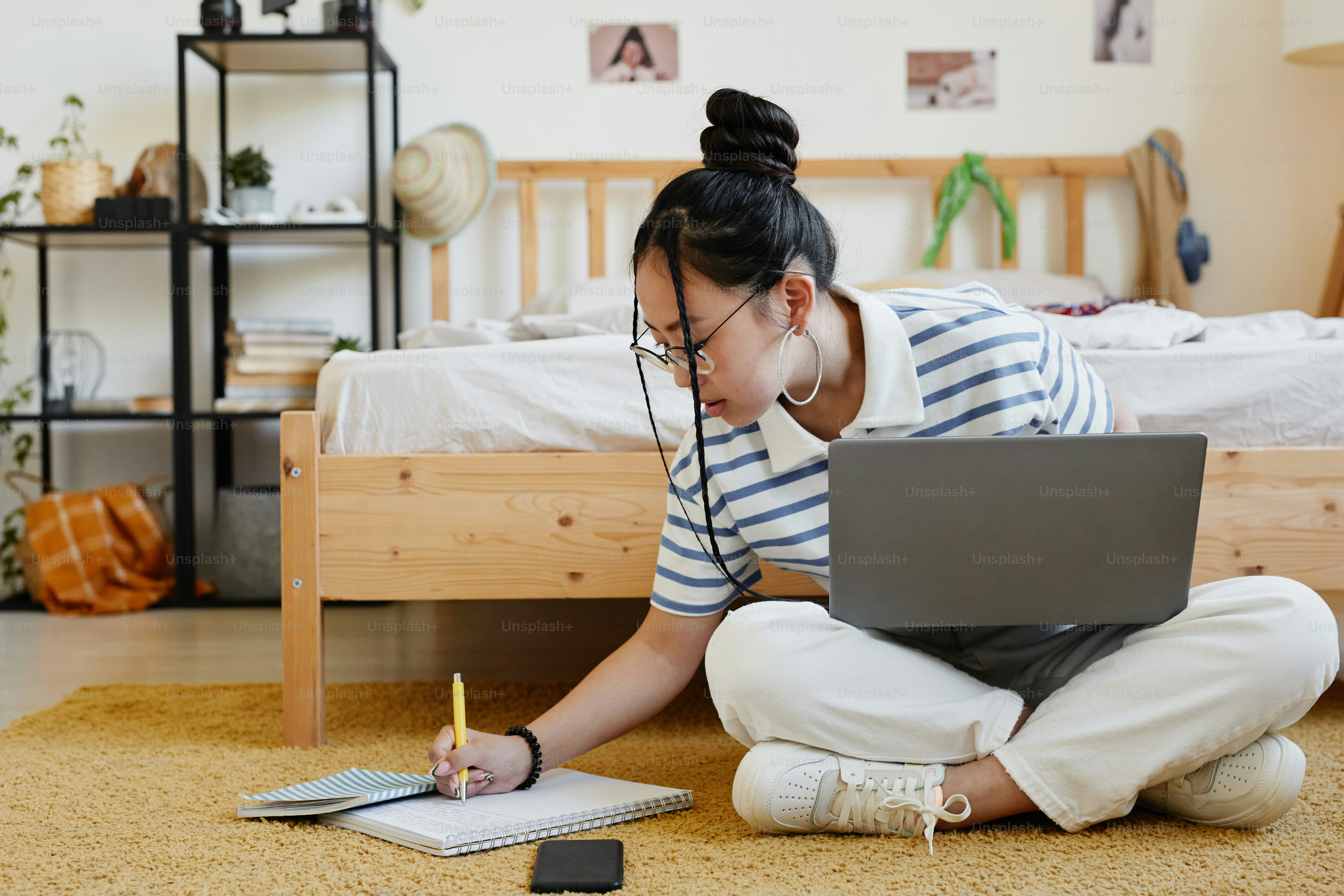 Potret panjang penuh gadis remaja Asia menggunakan laptop sambil duduk di lantai di rumah dan mengerjakan pekerjaan rumah, ruang salinan