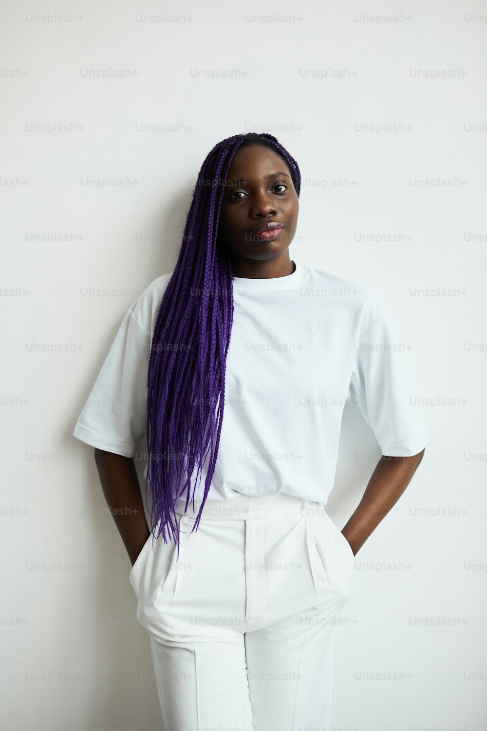 Minimal waist up portrait of contemporary African-American woman with colored hair looking at camera while posing against white background