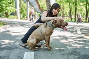 Our beloved home pets. Full length view of happy smiling woman embracing and stroking her favorite dog while walking on the summer street