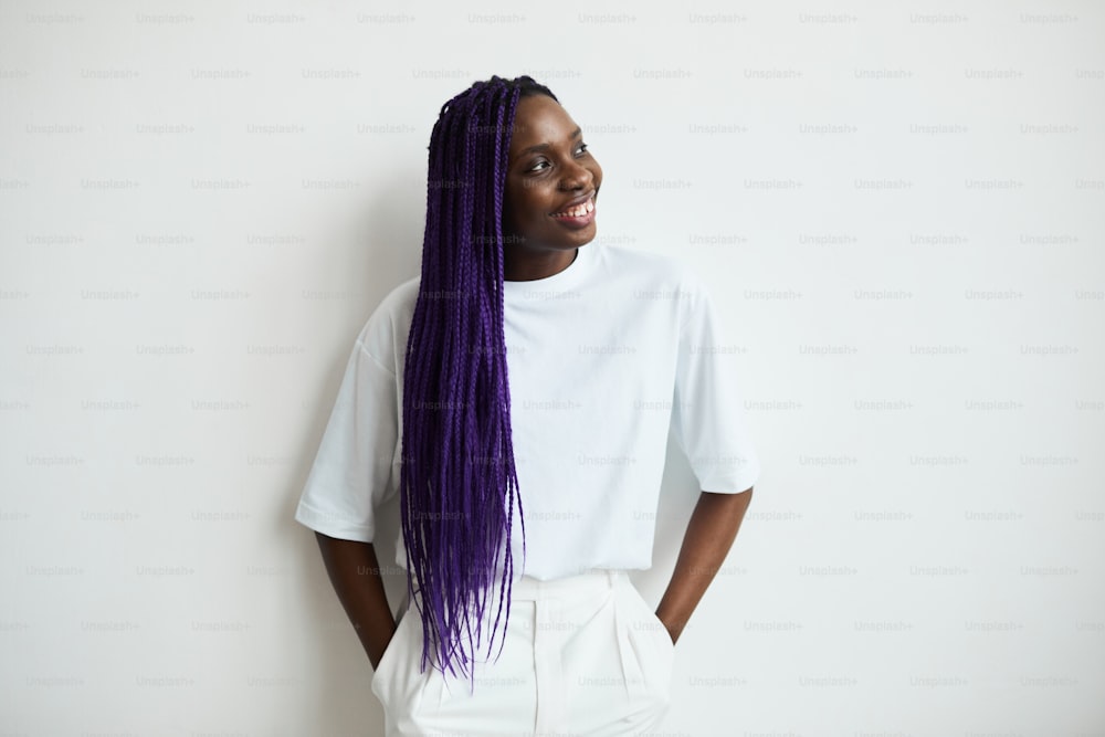 Minimal waist up portrait of carefree African-American woman with colored hair standing against white background, copy space