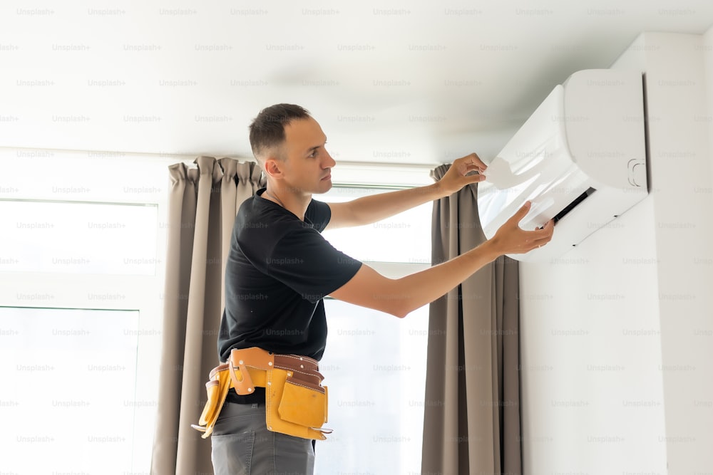 Rear View Of A Man Cleaning Air Conditioning System.