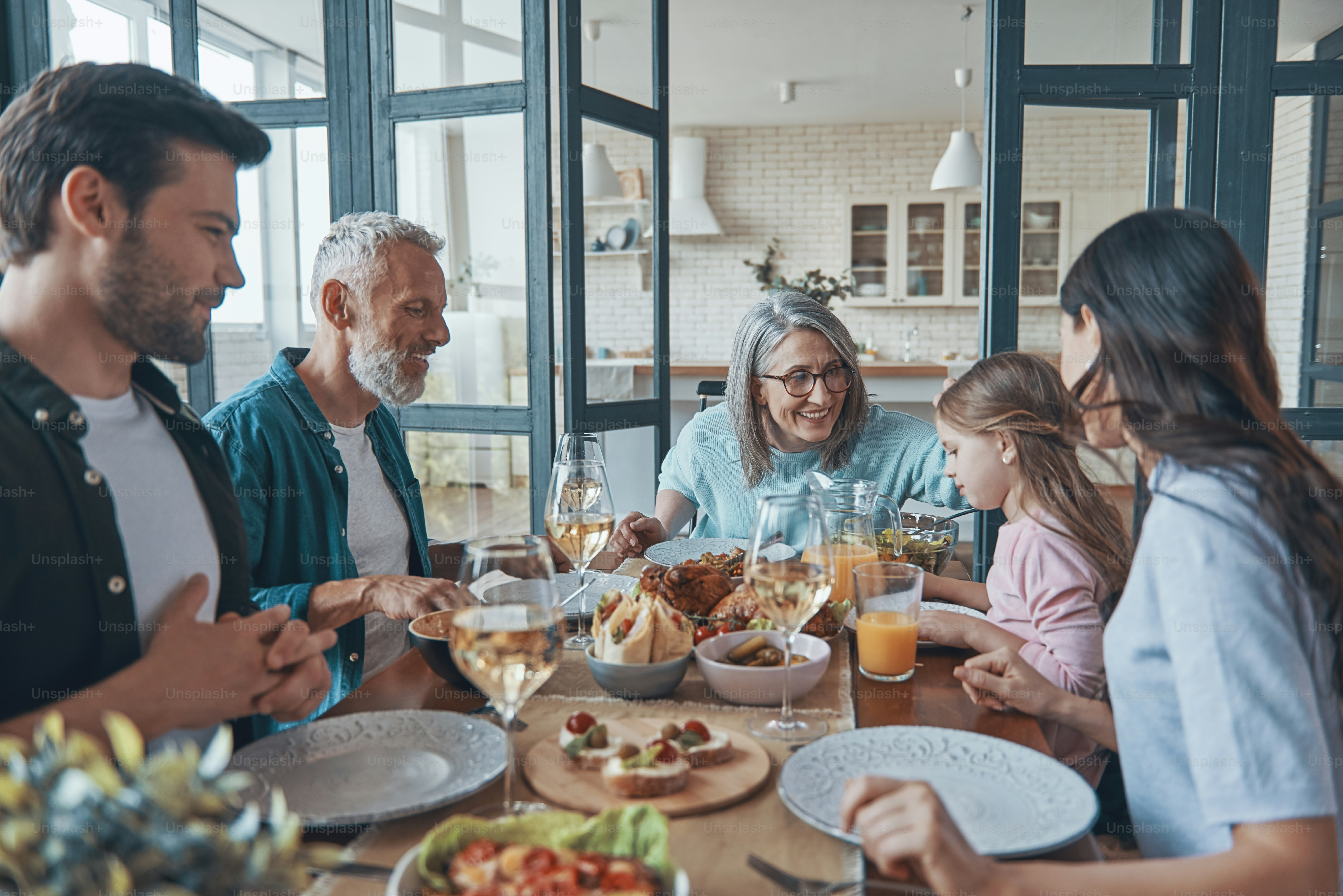 Famille multigénérationnelle heureuse souriante tout en dînant ensemble