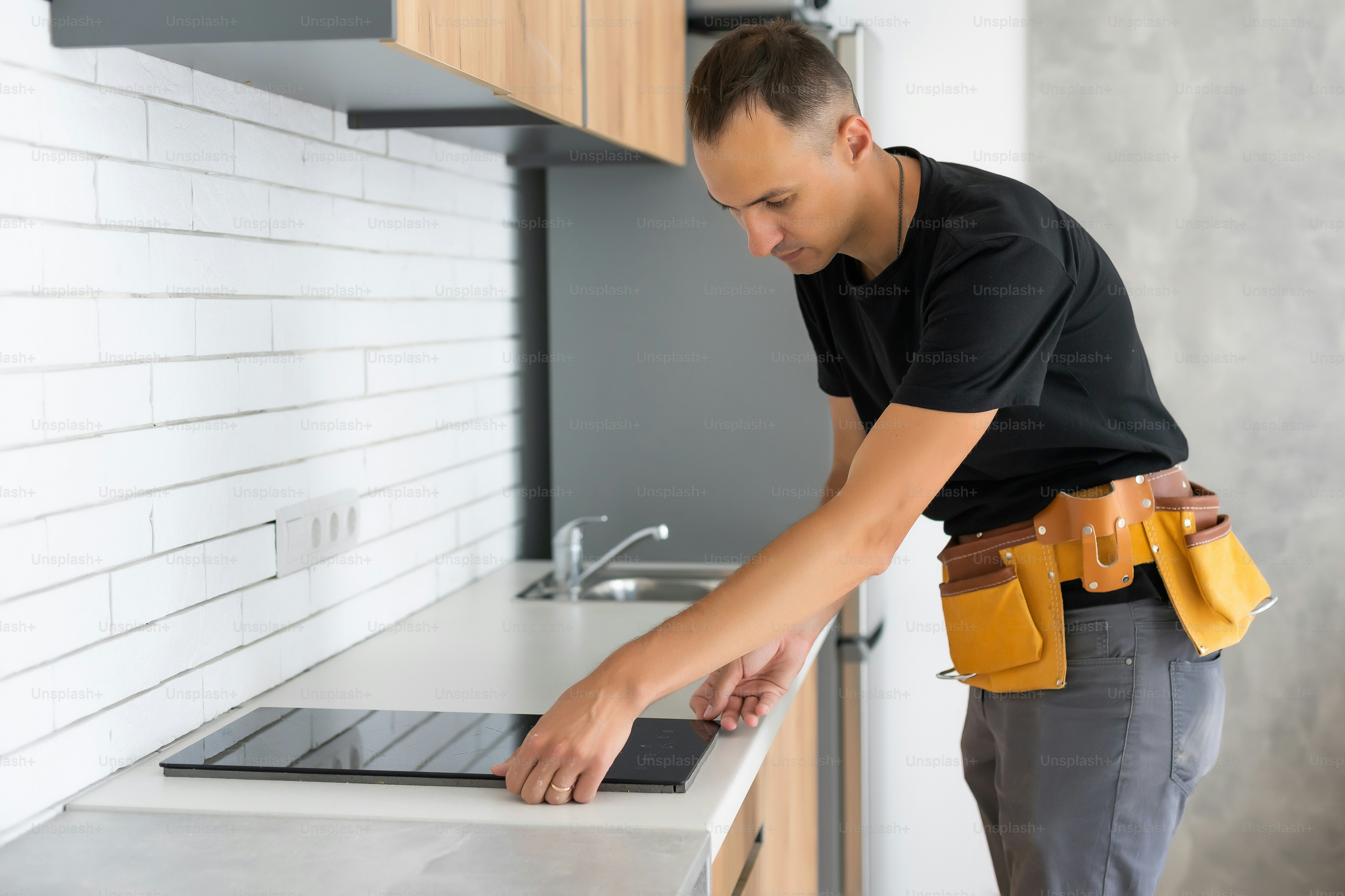 Young Repairman Installing Induction Cooker In Kitchen. photo ...