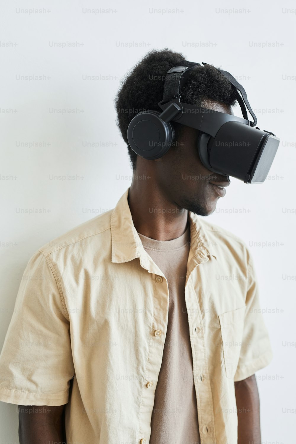 Close-up of African young man in VR glasses playing video game against the white background