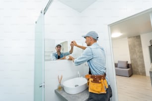 Handyman installing mirror in bathroom