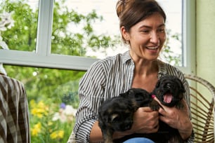 Portrait of cute woman spending time with little dogs in loggia