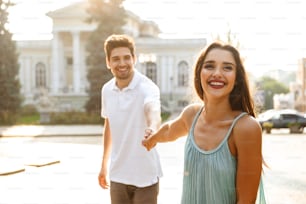 Imagen de una pareja feliz y linda y amorosa caminando al aire libre mientras se toman de la mano.