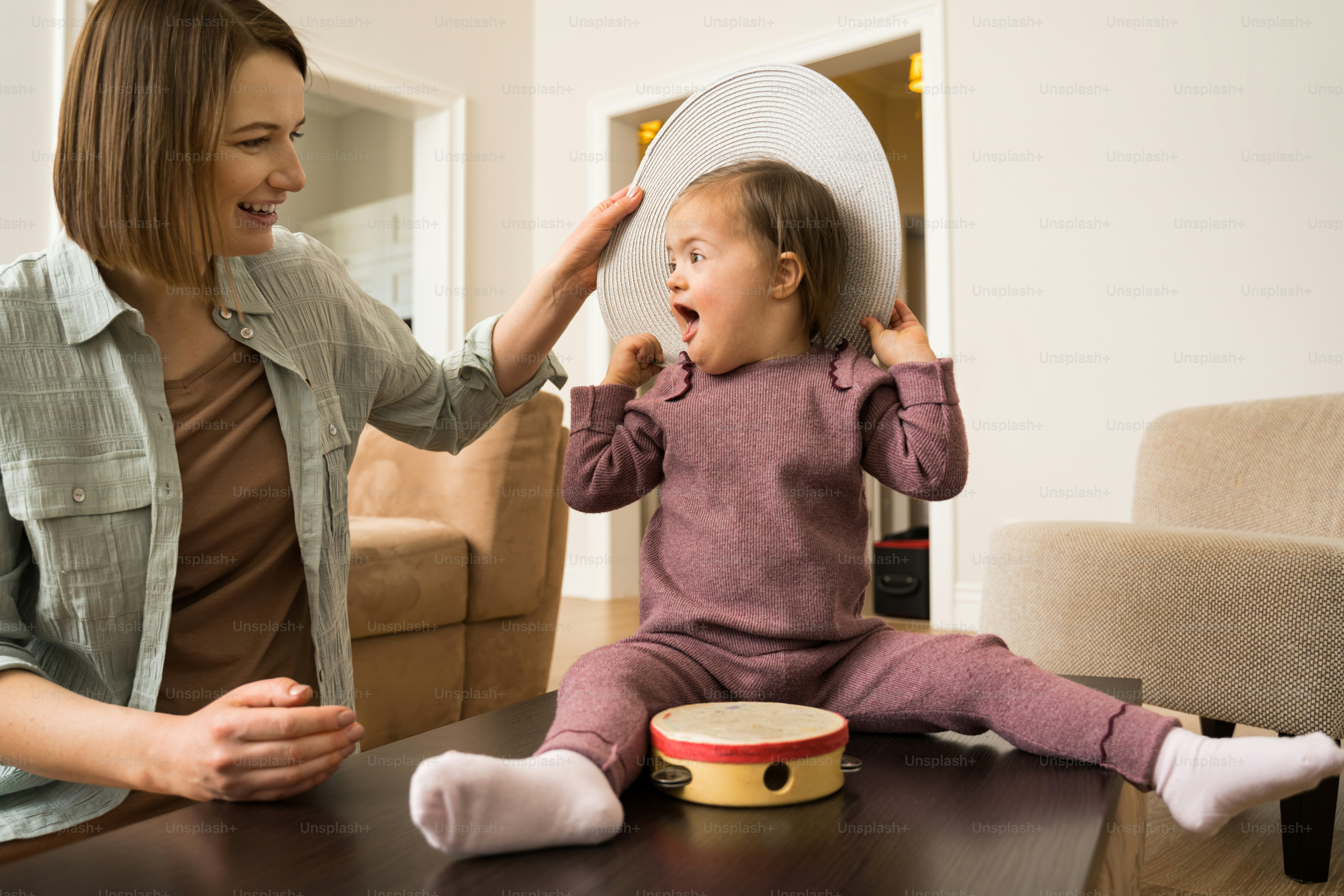 Peekaboo. Kleines süßes Mädchen mit Down-Syndrom, das mit seiner schönen Mutter am Peekaboo spielt und große Emotionen empfindet. Stockfotografie