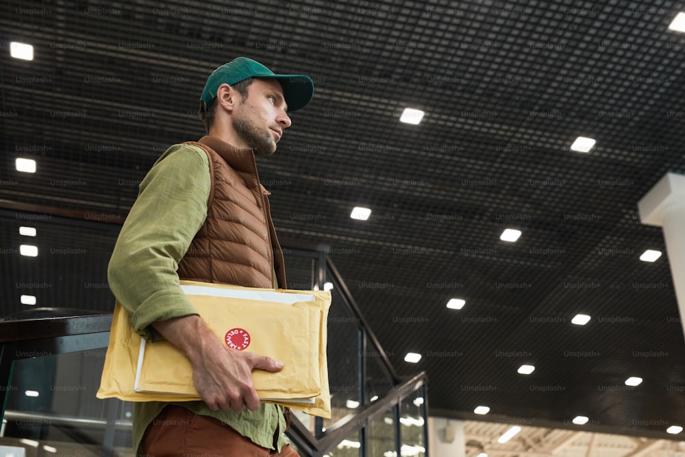 Side view portrait of delivery man holding parcels while entering office building, copy space
