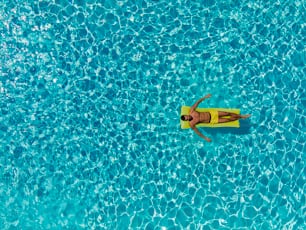 Vacation mood. Refreshment at the outdoor private pool on a sunny summer day. A man on a mattress in a pool. Aerial shot of a half-naked man floating on a mattress in a private resort