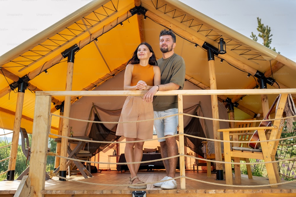 Happy young couple enjoying summer vacation at glamping house at luxurious resort