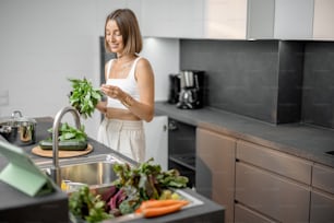 Junge Frau, die mit frischem Gemüse und Gemüse kocht, schaut sich das Rezept auf dem digitalen Tablet in der modernen Küche an. Frische Bio-Zutaten, Hygiene und gesundes Ernährungskonzept