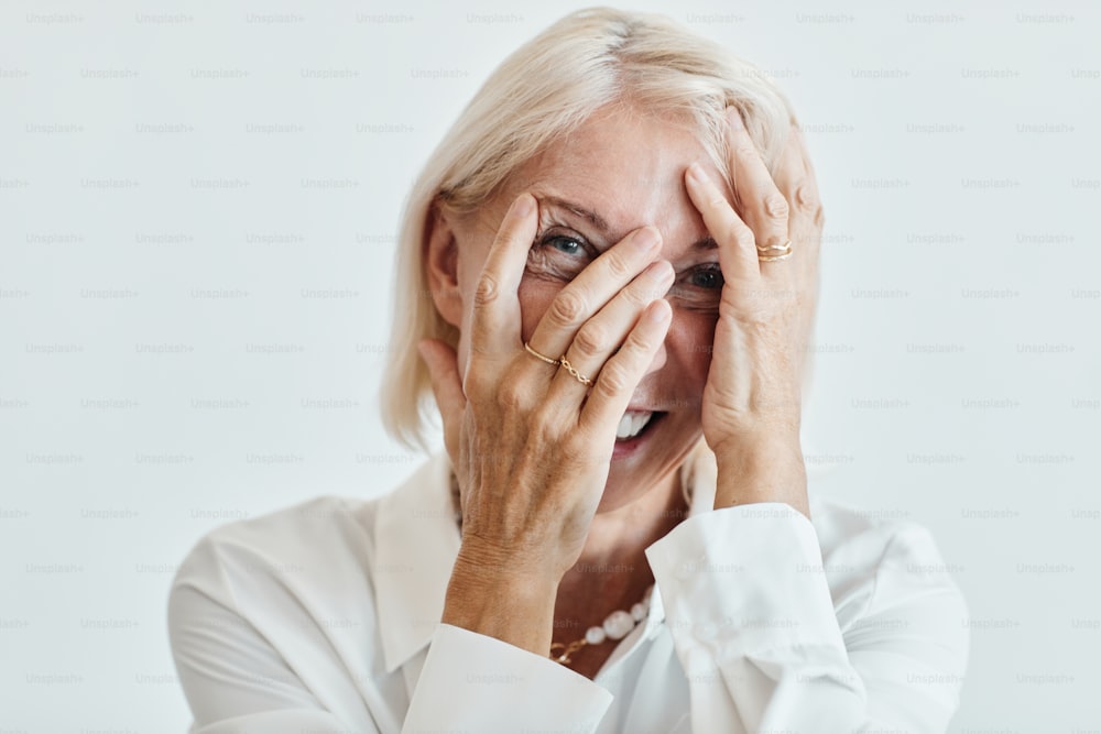 Close up portrait of elegant mature woman laughing carefree against white background, copy space