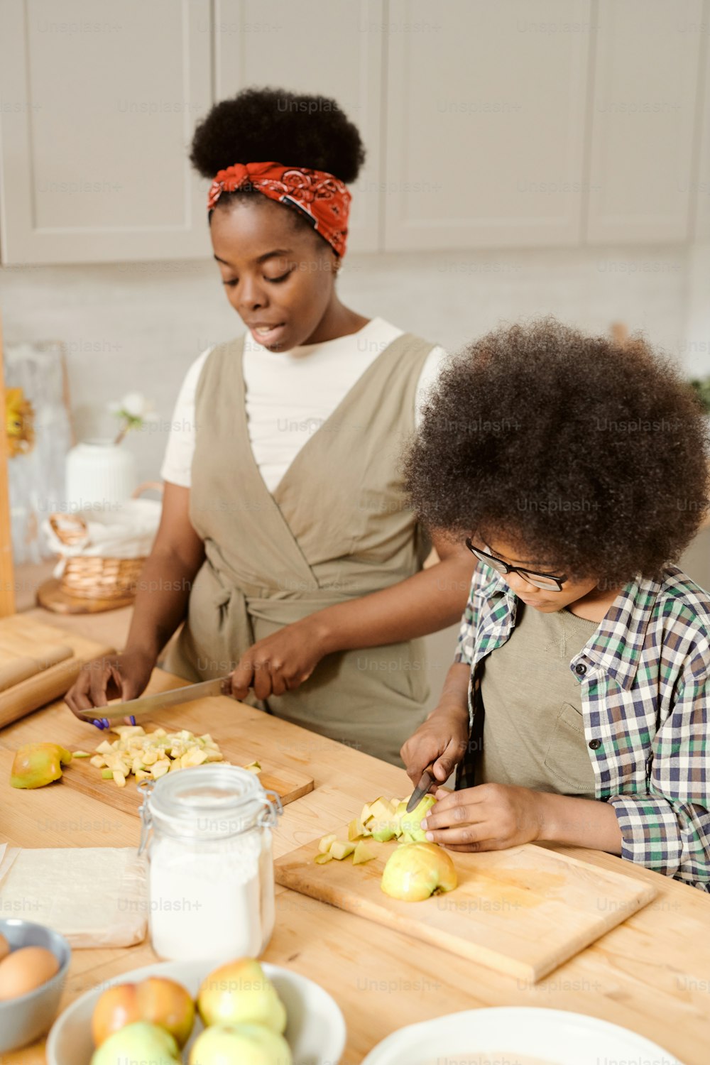 어린 소년과 그의 어머니는 아침 식사로 집에서 만든 과자를 위해 사과를 썰고 있다