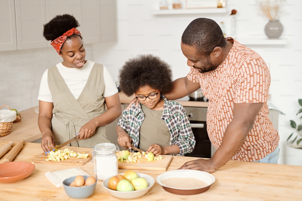 Young African family of three preparing breakfast by kitchen table