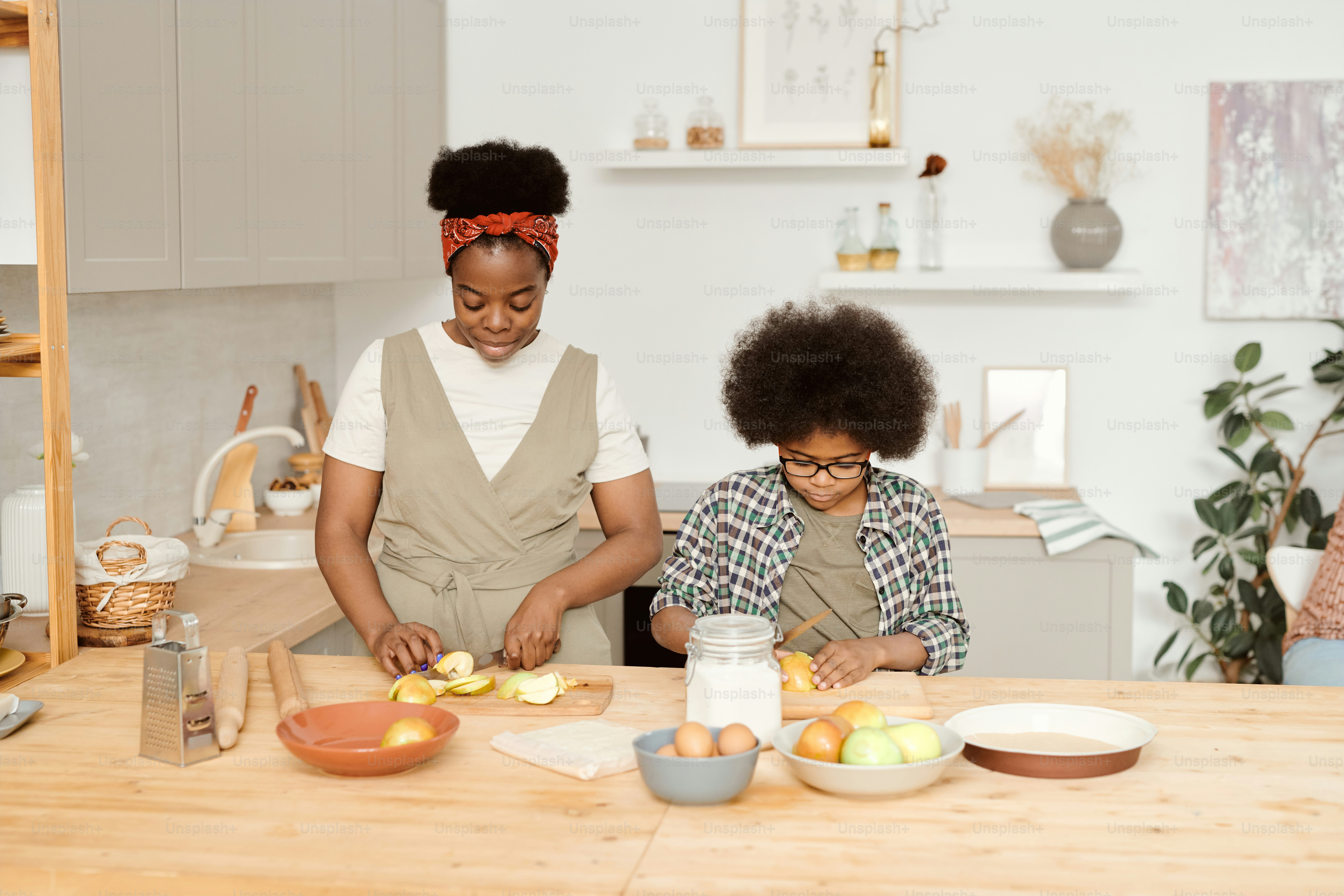 Cute little boy helping his mom with cooking lunch by kitchen table ...