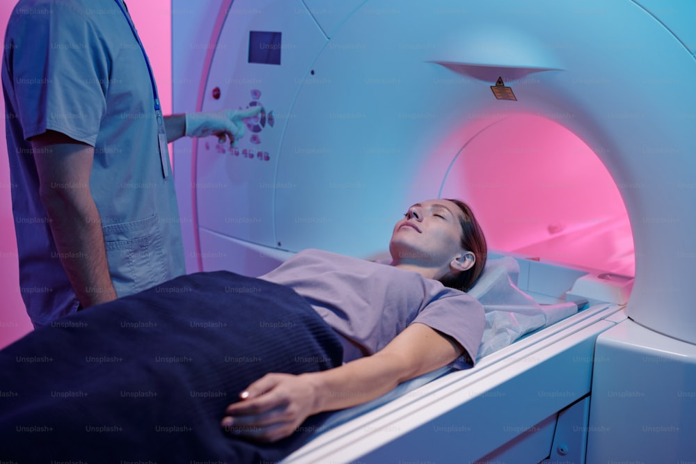 Mujer joven con los ojos cerrados esperando el inicio del examen de resonancia magnética