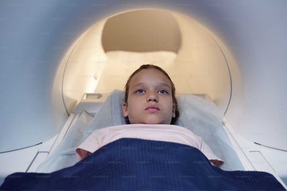 Contemporary little girl undergoing mri scan procedure in clinics or medical laboratory