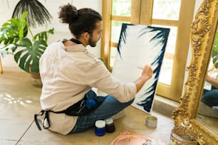 Vista traseira de um jovem criativo na casa dos 20 anos tendo uma aula de pintura em uma oficina