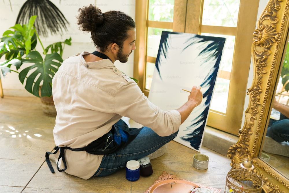 Vista trasera de un joven creativo de unos 20 años tomando una clase de pintura en un taller