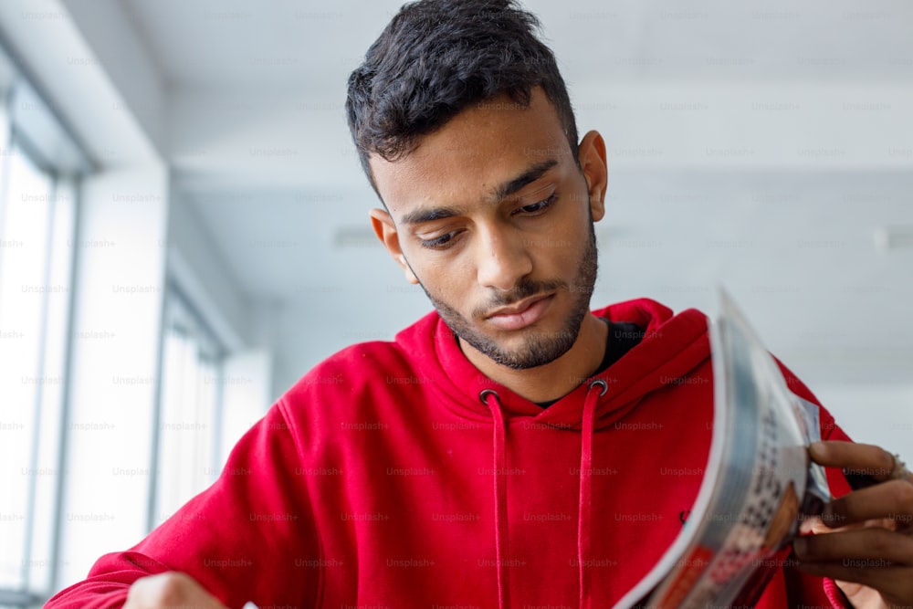 a man in a red hoodie reading a newspaper