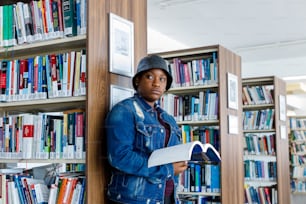 a woman leaning against a book shelf in a library