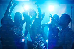 Menina alegre cercada por amigos dançantes na discoteca