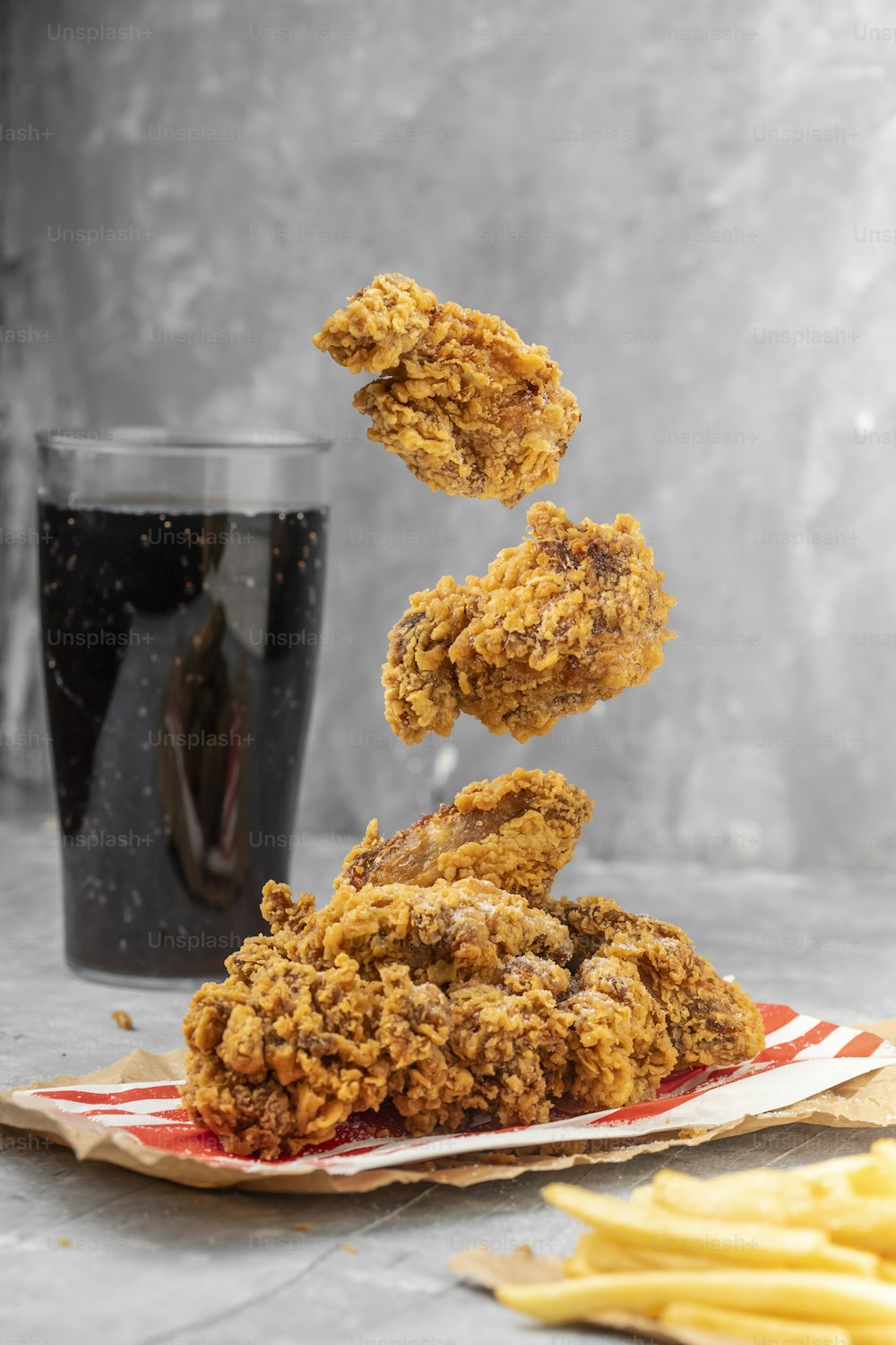 a pile of fried chicken sitting on top of a plate next to fries