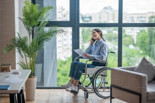 Phone call. A cute girl on a wheel chair talking on the phone and smiling