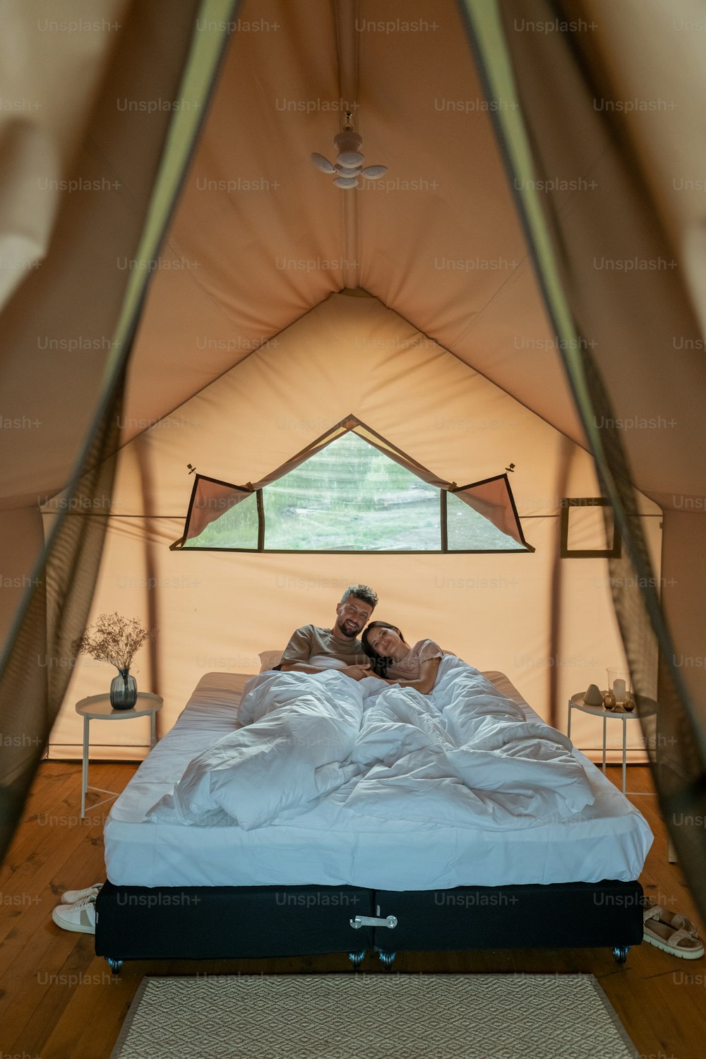 Giovane coppia amorosa che riposa nel letto sotto la coperta bianca al mattino all'interno della tenda glamping