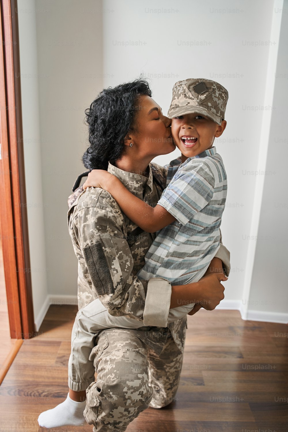 Famiglia felice. Gioiosa madre militare felice e suo figlio si guardano e sorridono divertendosi. Donna che bacia il suo figlio dopo la riunione
