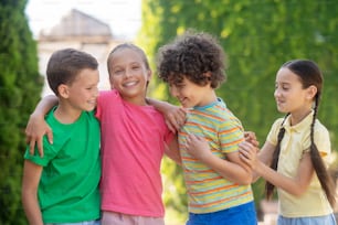 Liking. Smiling boys and girls of primary school age socializing hugging showing liking in park on summer day